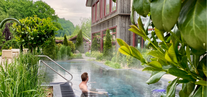 På bilden badar en man i den stora utomhuspoolen som håller 39 grader. Utomhuspoolen är en del av Sinnenas spa och spaträdgården på Ästad vingård i Halland